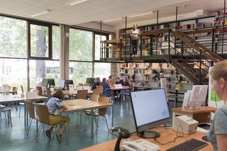 Großer Lesesaal mit Arbeitsplätzen, Empore, Bücherregalen und Ausleihtheke